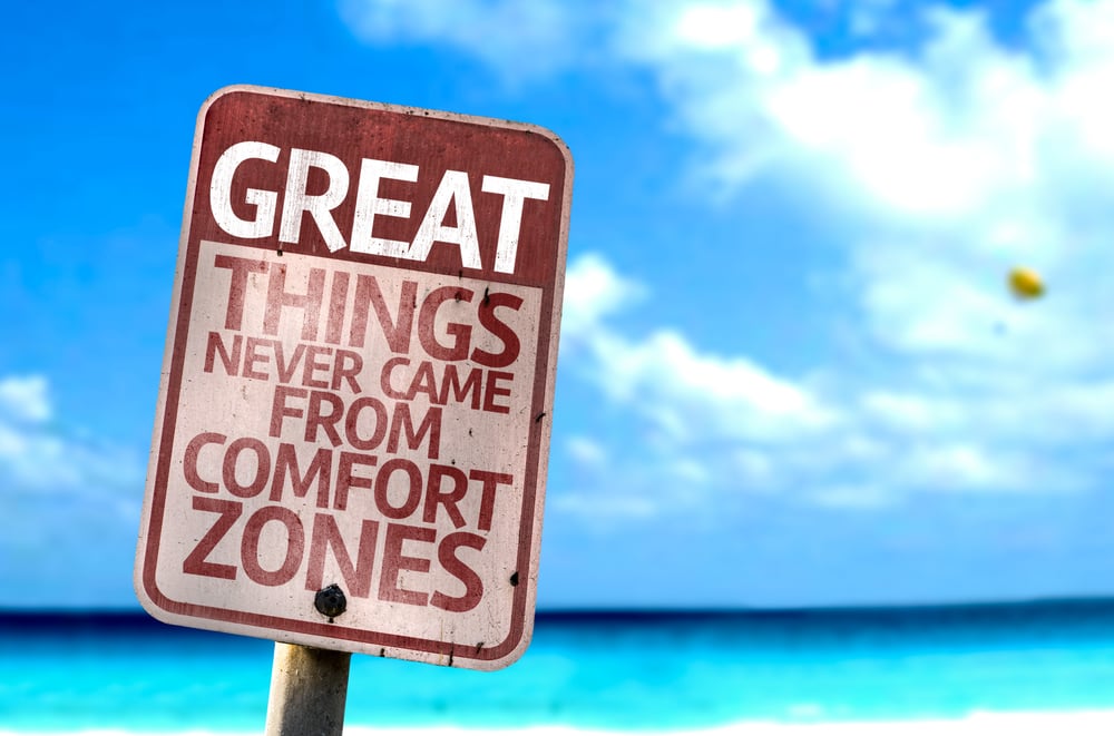 Great Things Never Came From Comfort Zones sign with a beach on background
