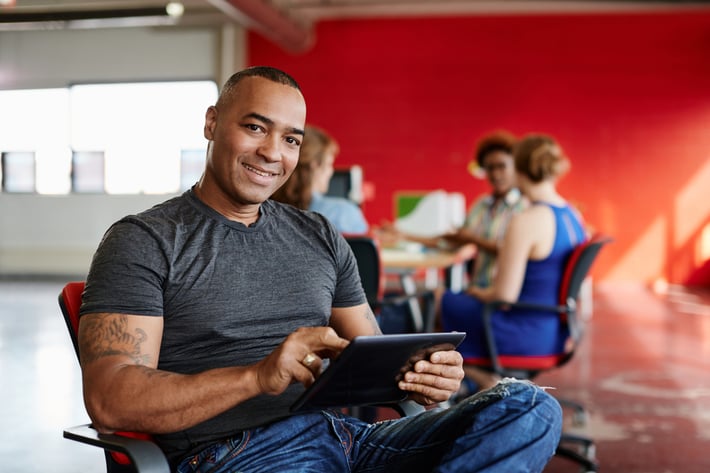 Confident male designer working on a digital tablet in red creative office space