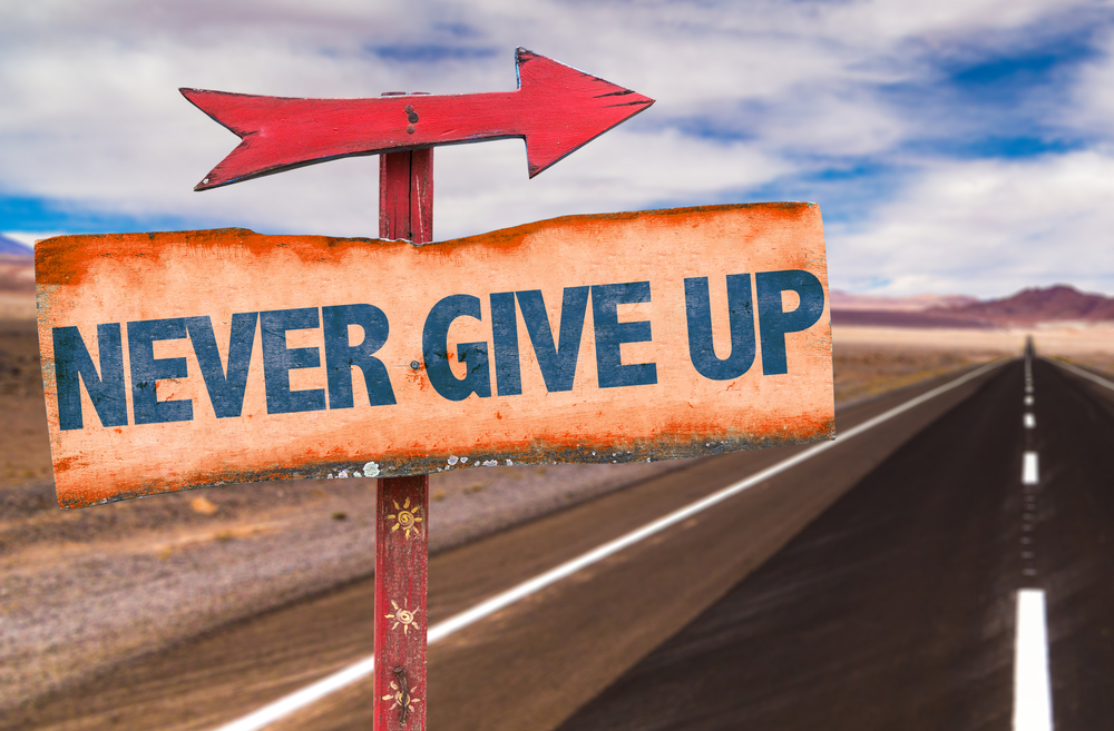 Never Give Up sign with road background